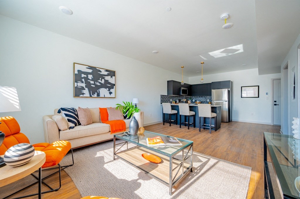A modern living room with a glass coffee table and orange chairs.