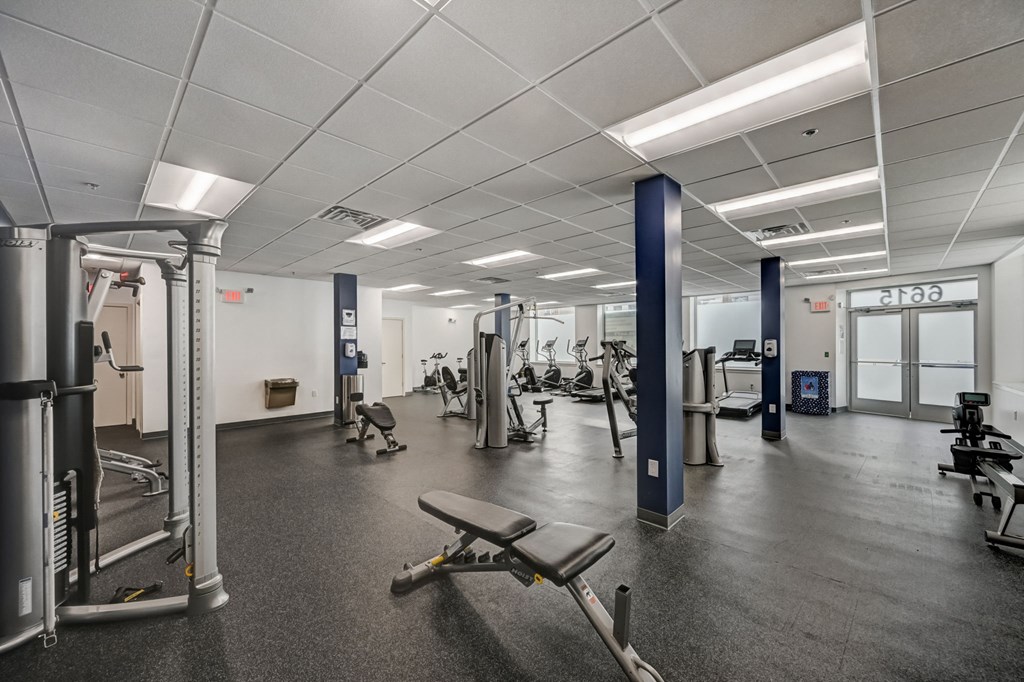 a gym with weights and cardio equipment in a building with white walls