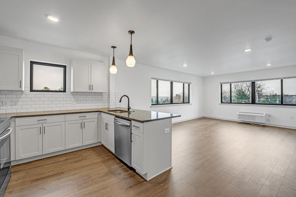 an open kitchen and living room with white cabinets and wood floors