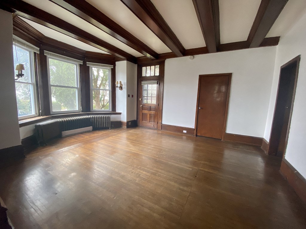 an empty living room with wood floors and large windows