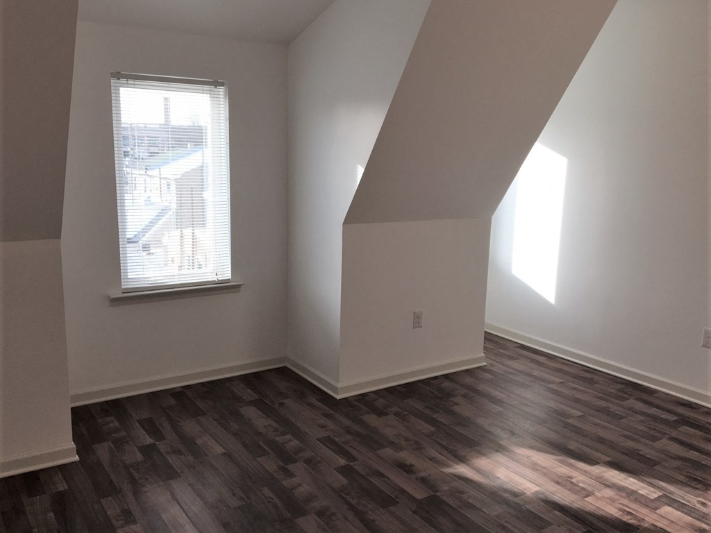 an empty living room with wood floors and a window