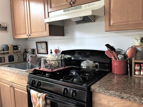 A kitchen with a black stove top oven and wooden cabinets.
