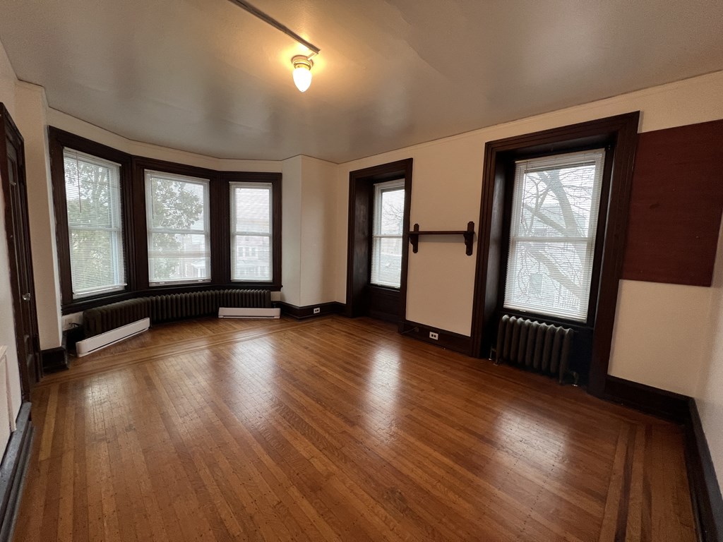 an empty living room with wood floors and large windows