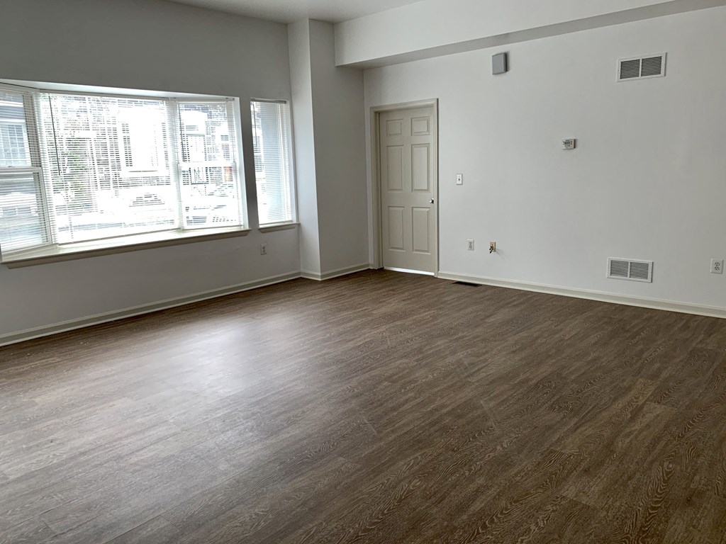 an empty living room with wood flooring and a window