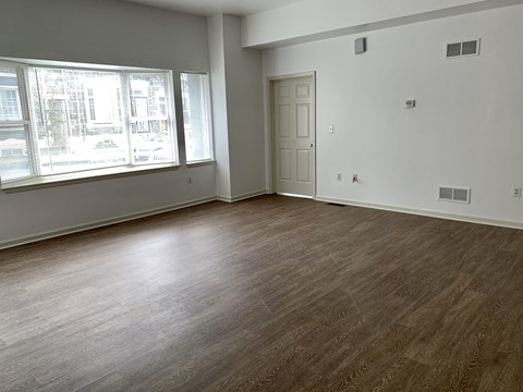 an empty living room with wood flooring and a window