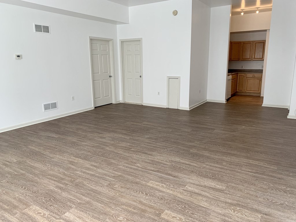 an empty living room with a wood floor and white walls