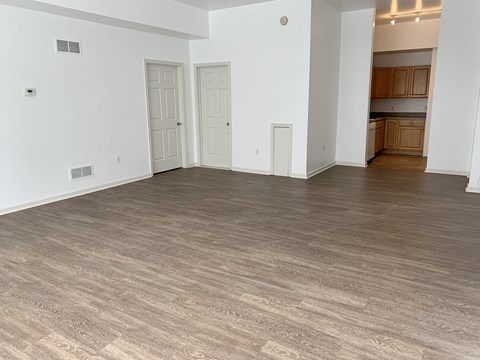 an empty living room with a wood floor and white walls
