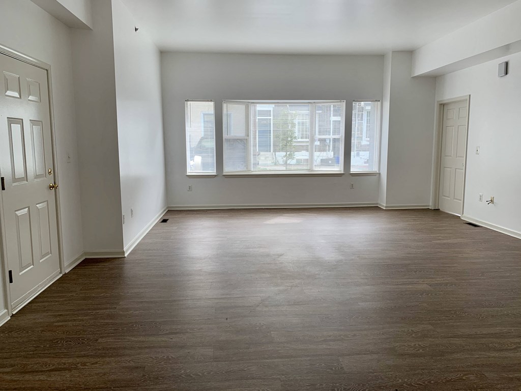 an empty living room with a large window and wood floors