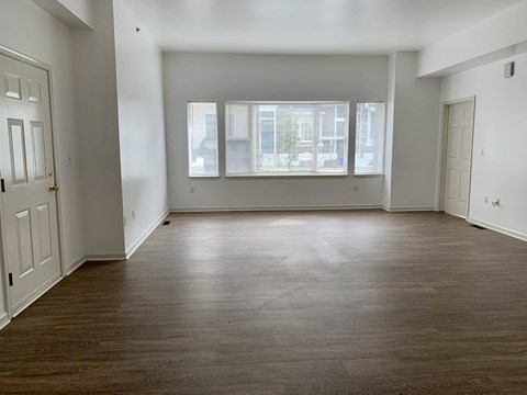 an empty living room with a large window and wood floors