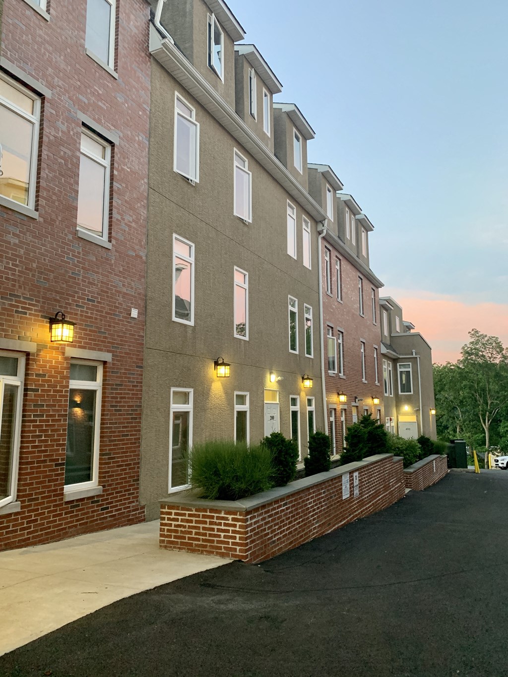 a brick apartment building at dusk with a sidewalk