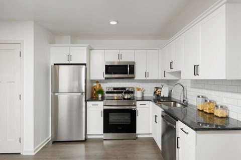 a white kitchen with stainless steel appliances and white cabinets