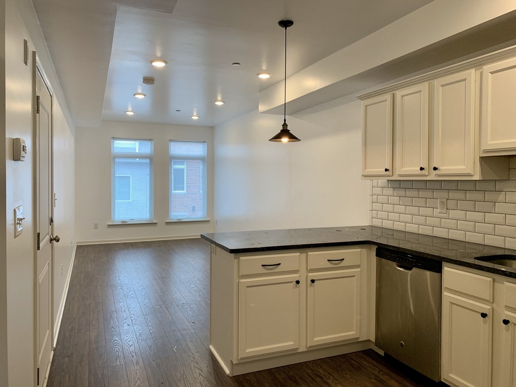 a kitchen with white cabinets and a black counter top