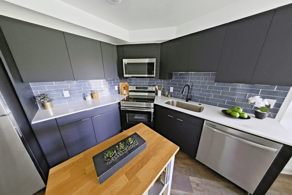 A modern kitchen with a wooden table and stainless steel appliances.