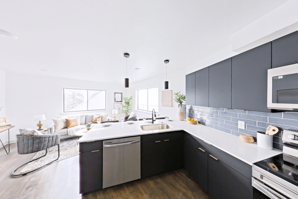 A modern kitchen with dark grey cabinets and a white countertop.