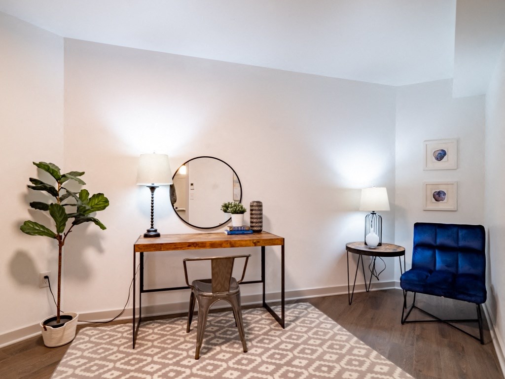 a living room with a desk with a mirror and a blue chair