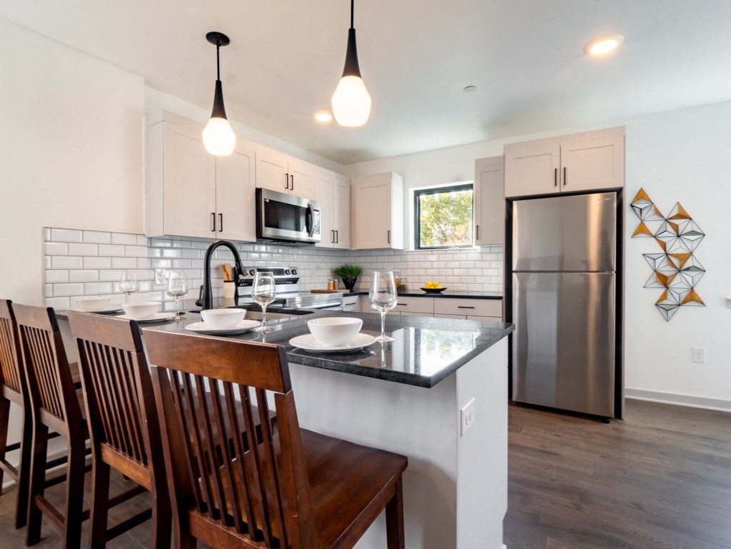 an open kitchen and dining area with a island and stainless steel refrigerator