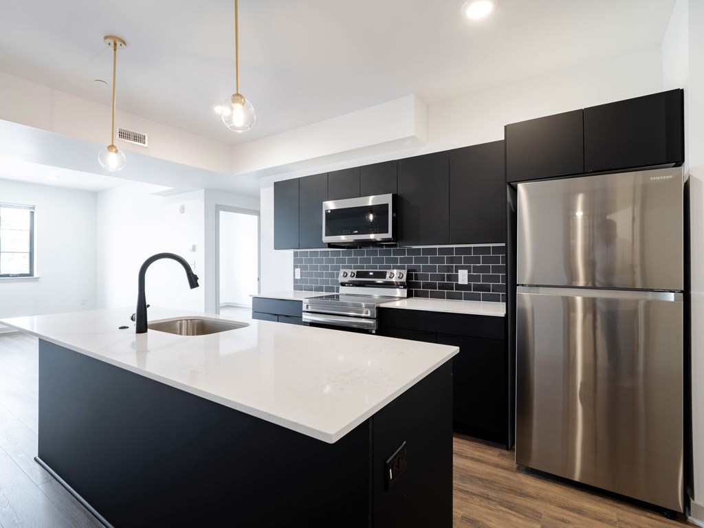 A modern kitchen with a stainless steel refrigerator and a black and white countertop.