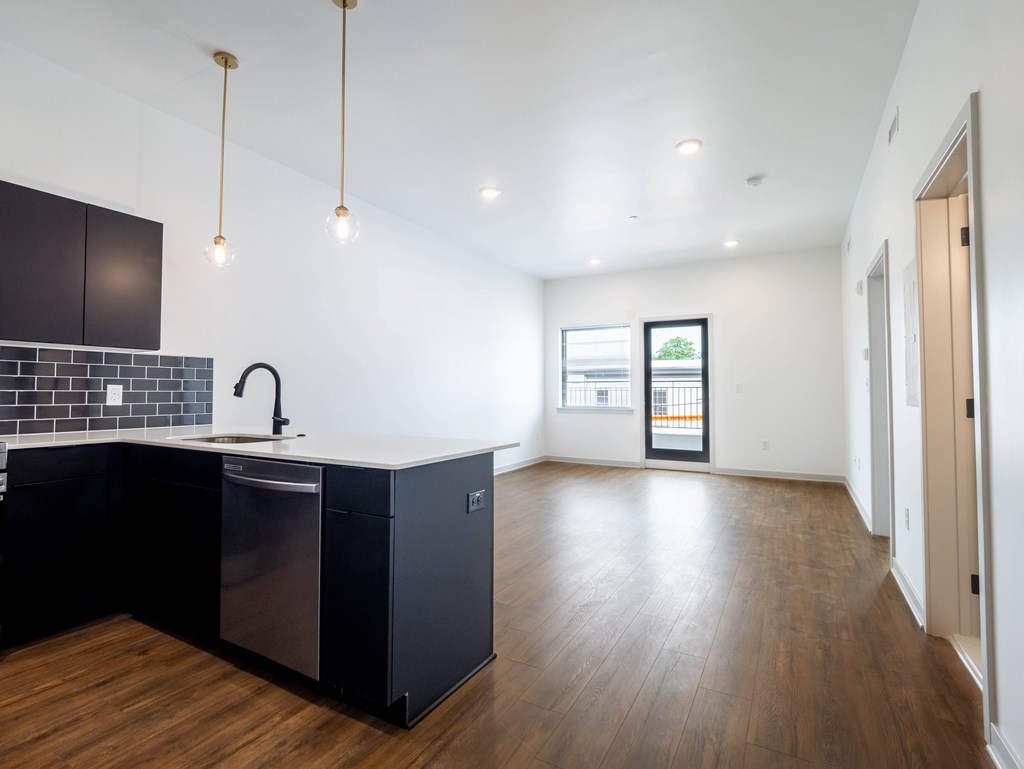 A kitchen with black cabinets and a wooden floor.