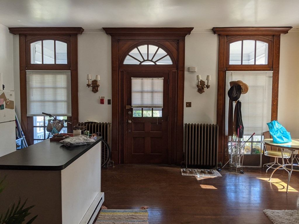 a living room with a wooden door and a kitchen with a table and chairs