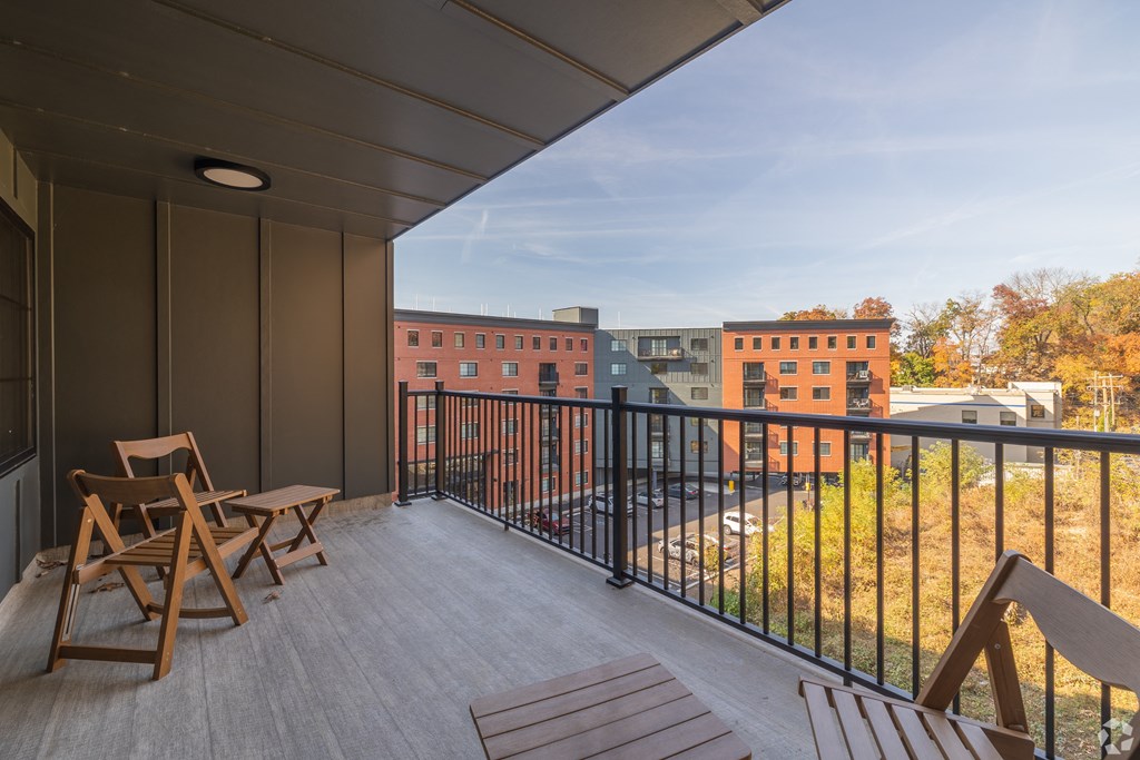A balcony with a table and chairs overlooking a cityscape.