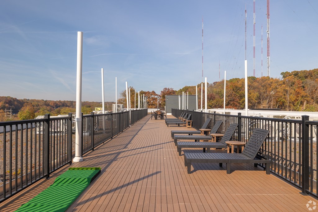 A long wooden deck with benches and a green mat on the ground.