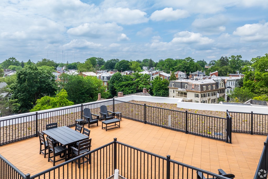 A balcony with a table and chairs overlooks a residential area.