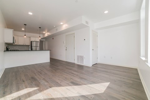 A spacious room with wooden flooring and white walls.