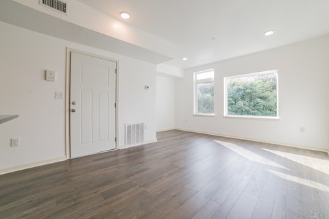 A room with a white door and a window with a view of trees.