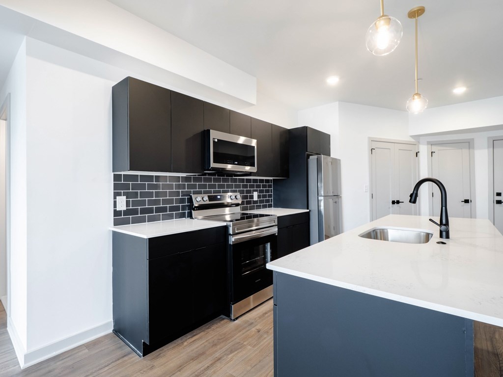 A modern kitchen with black cabinets and a white countertop.