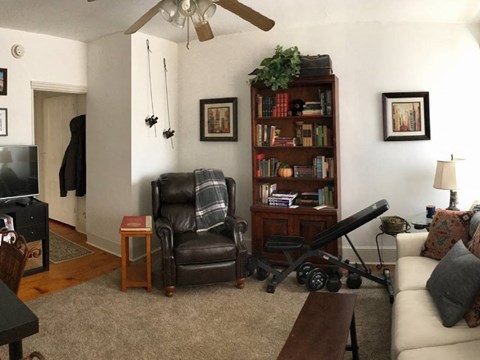 A living room with a black leather chair and a wooden bookshelf.