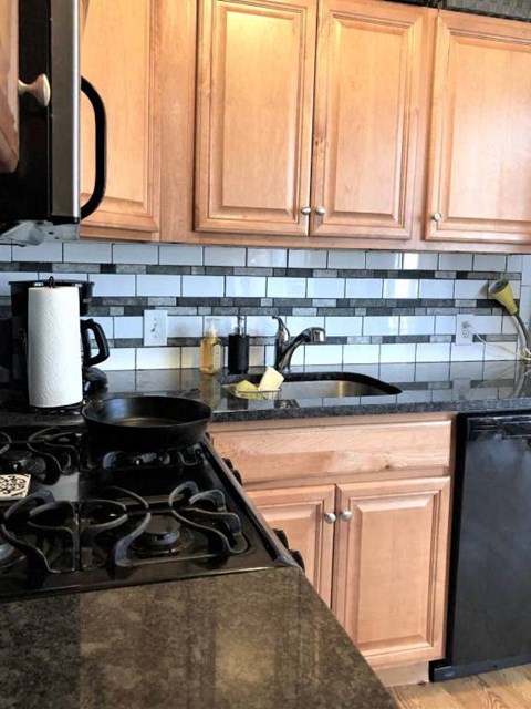 a kitchen with a stove and sink and wooden cabinets