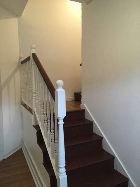 a stairway with a white railing and brown stairs