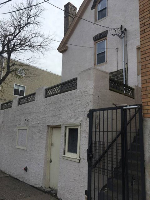 the front of a white house with a black gate