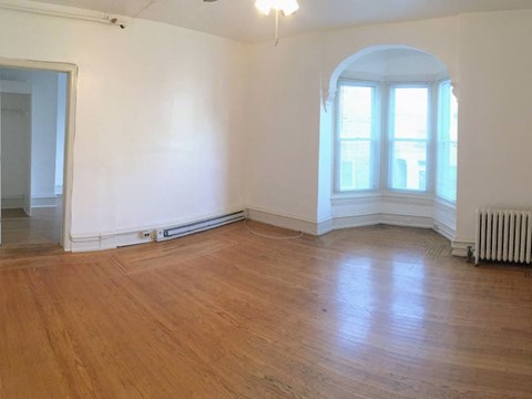 an empty living room with wooden floors and a window
