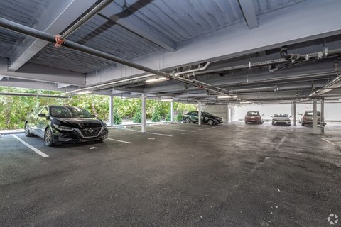 A black car is parked in a spacious, multi-level parking garage.