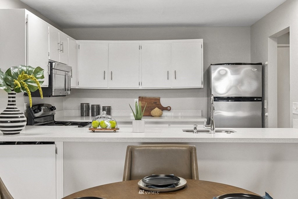 a kitchen with white cabinets and a table and a refrigerator