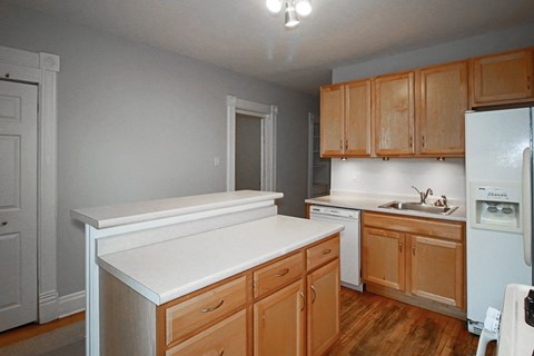 an empty kitchen with wooden cabinets and a white counter top