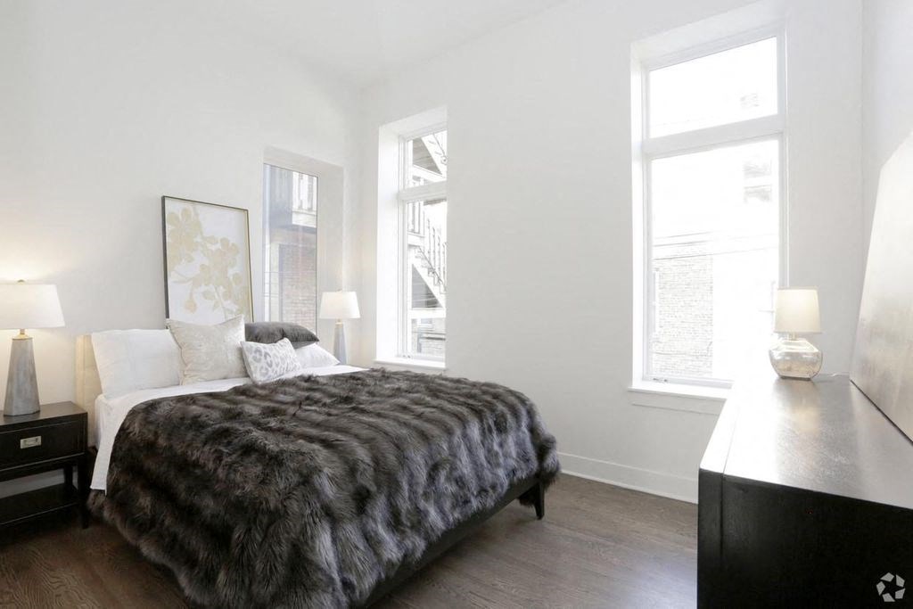 a bedroom with a bed and two windows