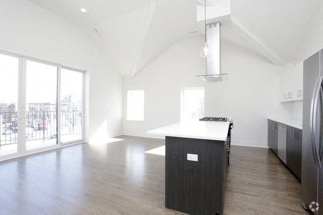 an empty room with a kitchen and a large window