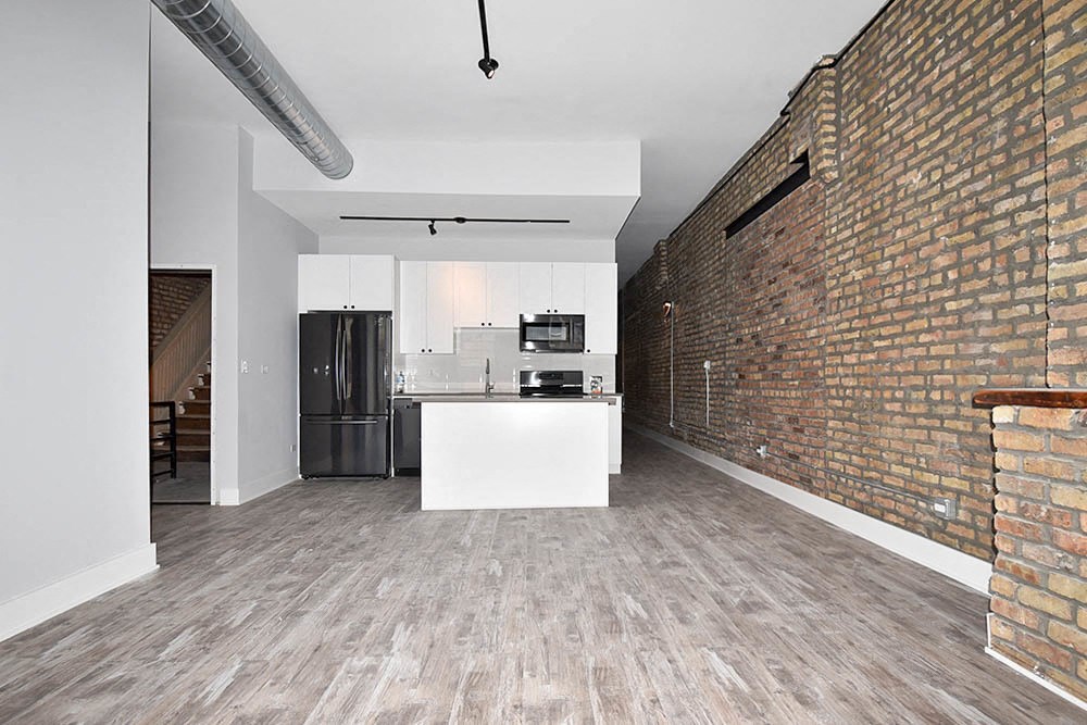 an empty room with a kitchen and a brick wall
