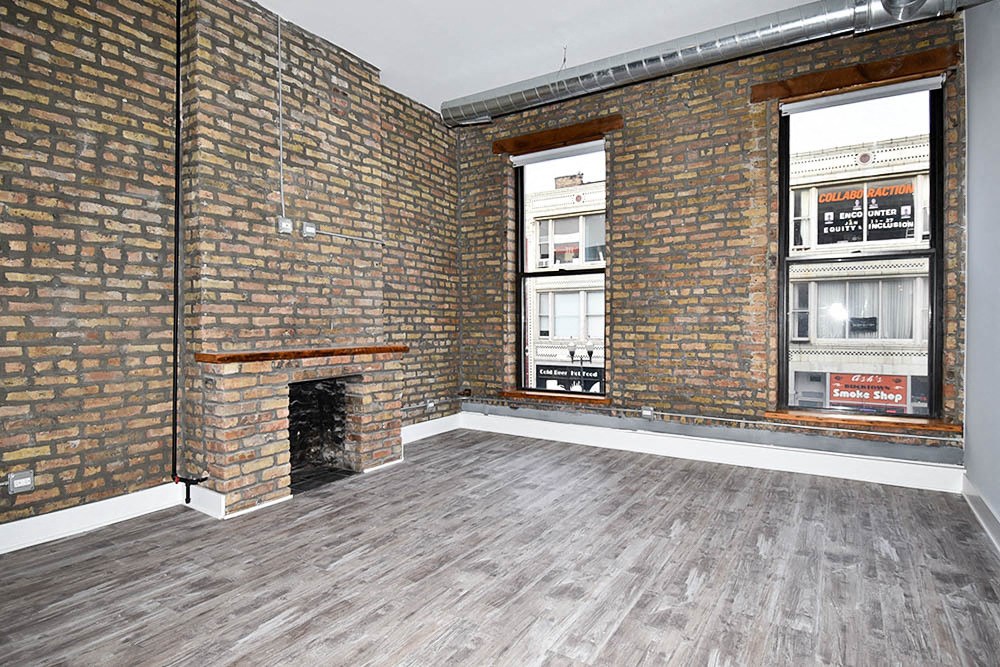 the living room of an empty apartment with brick walls and a fireplace