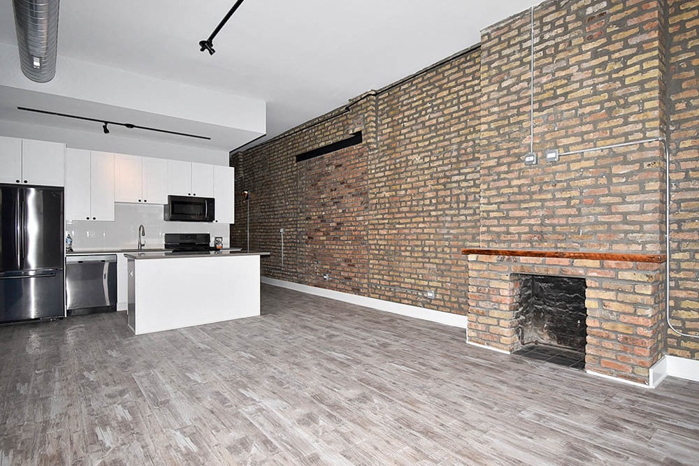 an empty living room with a brick wall and a fireplace