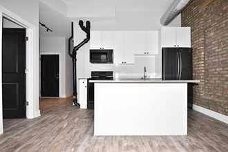 a white kitchen with a large island and a black refrigerator