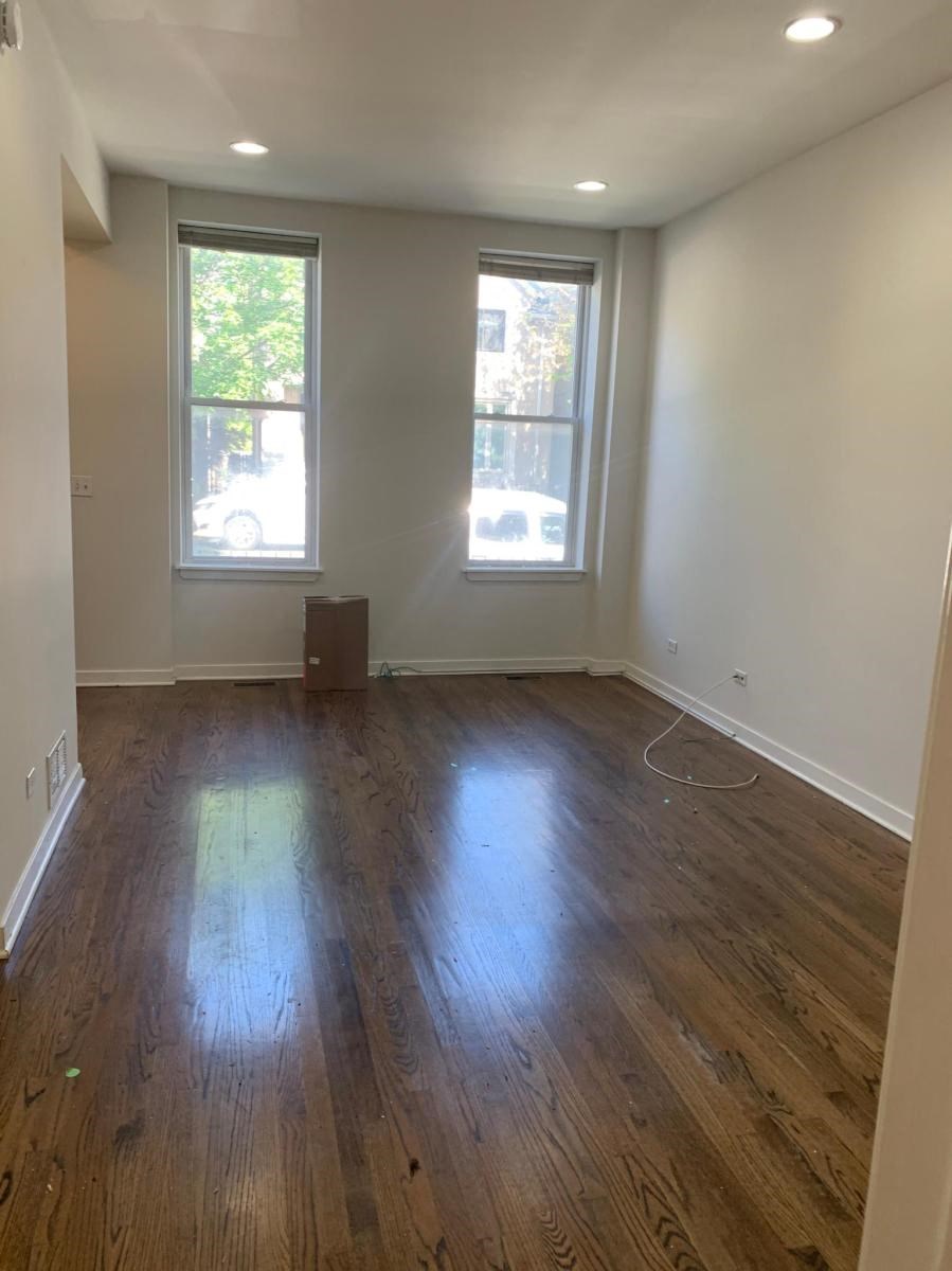 a living room with a hard wood floor and two windows