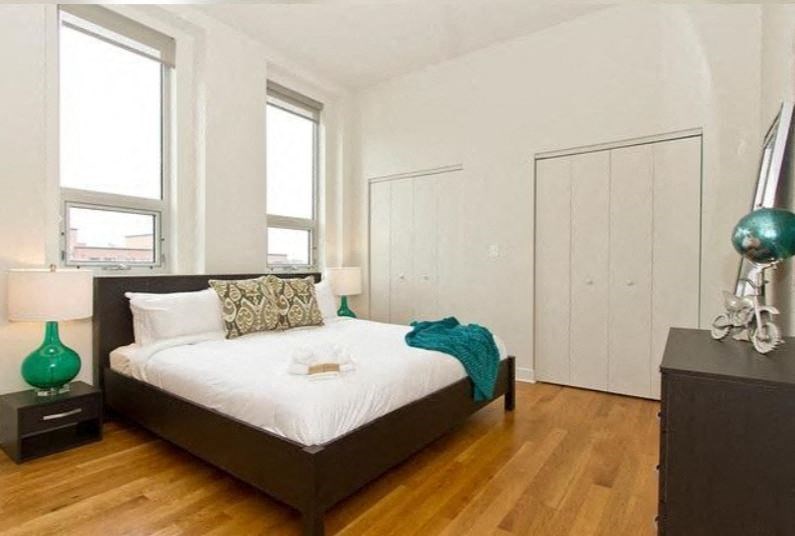 a bedroom with a bed and two windows