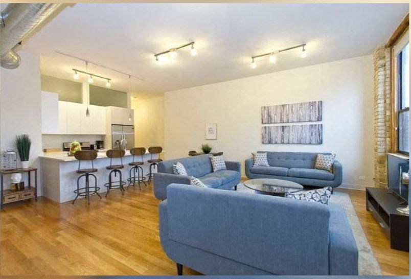 a living room and kitchen with blue couches and a table