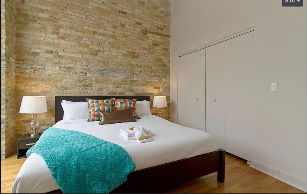 a bedroom with a bed and a brick wall