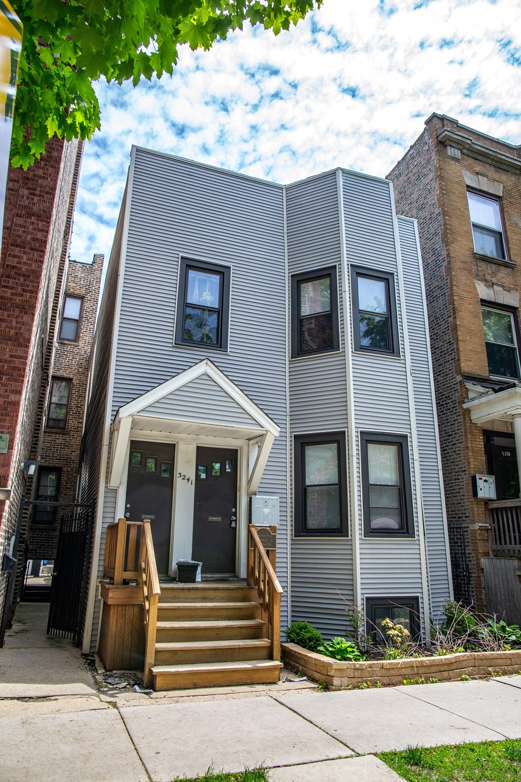 the exterior of a gray house with a wooden porch and stairs
