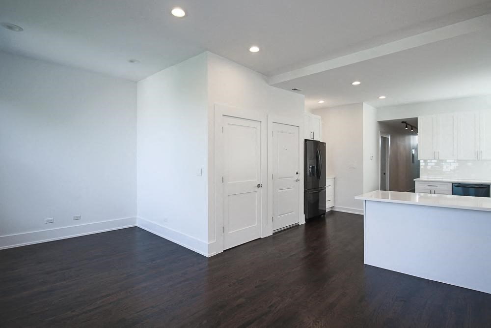 an empty living room and kitchen with white walls and wood floors