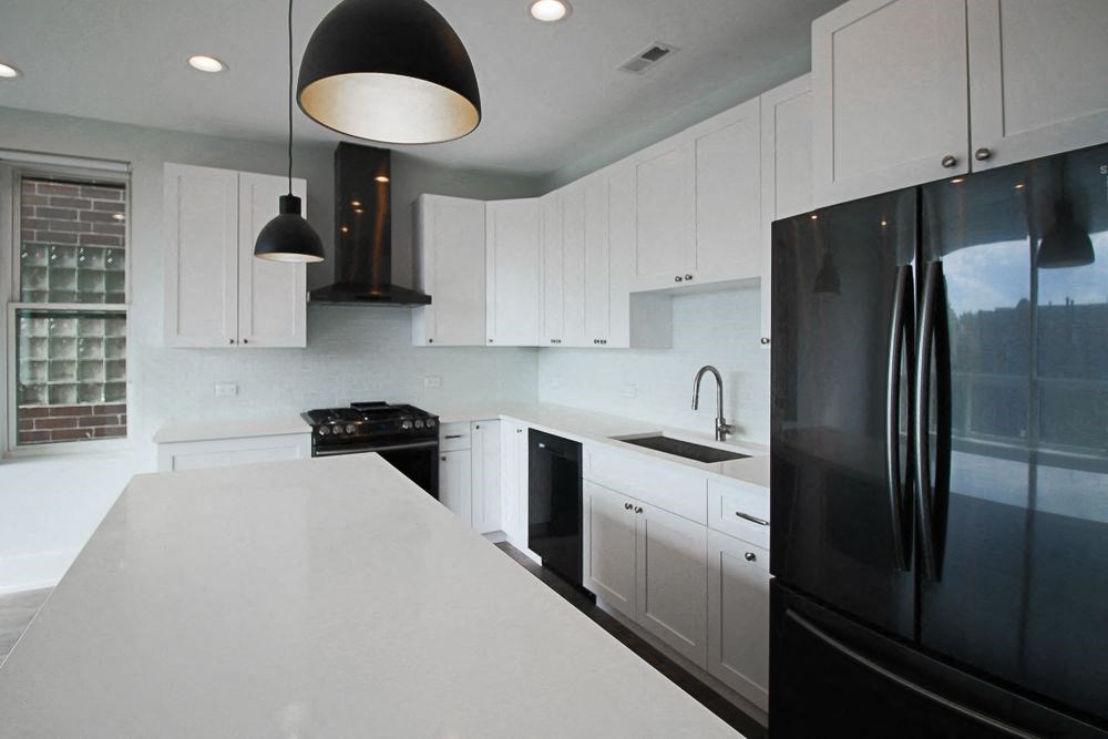 a white kitchen with black appliances and white counter tops